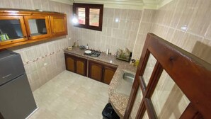 A compact kitchen with a built-in gas stove, a sink, and wooden cabinets. - Charming 2-bedroom apartment with WiFi, AC in superb Fès (Fès)
