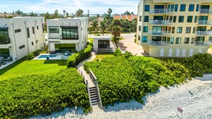 A modern residential area with a pool, lush greenery, and a sandy beach. - Newly Renovated | Luxe Condo w/ Riverfront Views, Pool & Resort Amenities! (Melbourne Beach)