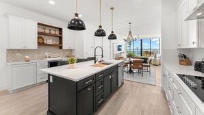 A modern kitchen with a central island, white cabinetry, and pendant lighting. - Newly Renovated | Luxe Condo w/ Riverfront Views, Pool & Resort Amenities! (Melbourne Beach)