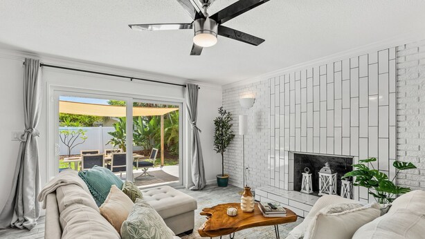 Una sala de estar moderna con chimenea, paredes de ladrillo blanco y un ventilador de techo.