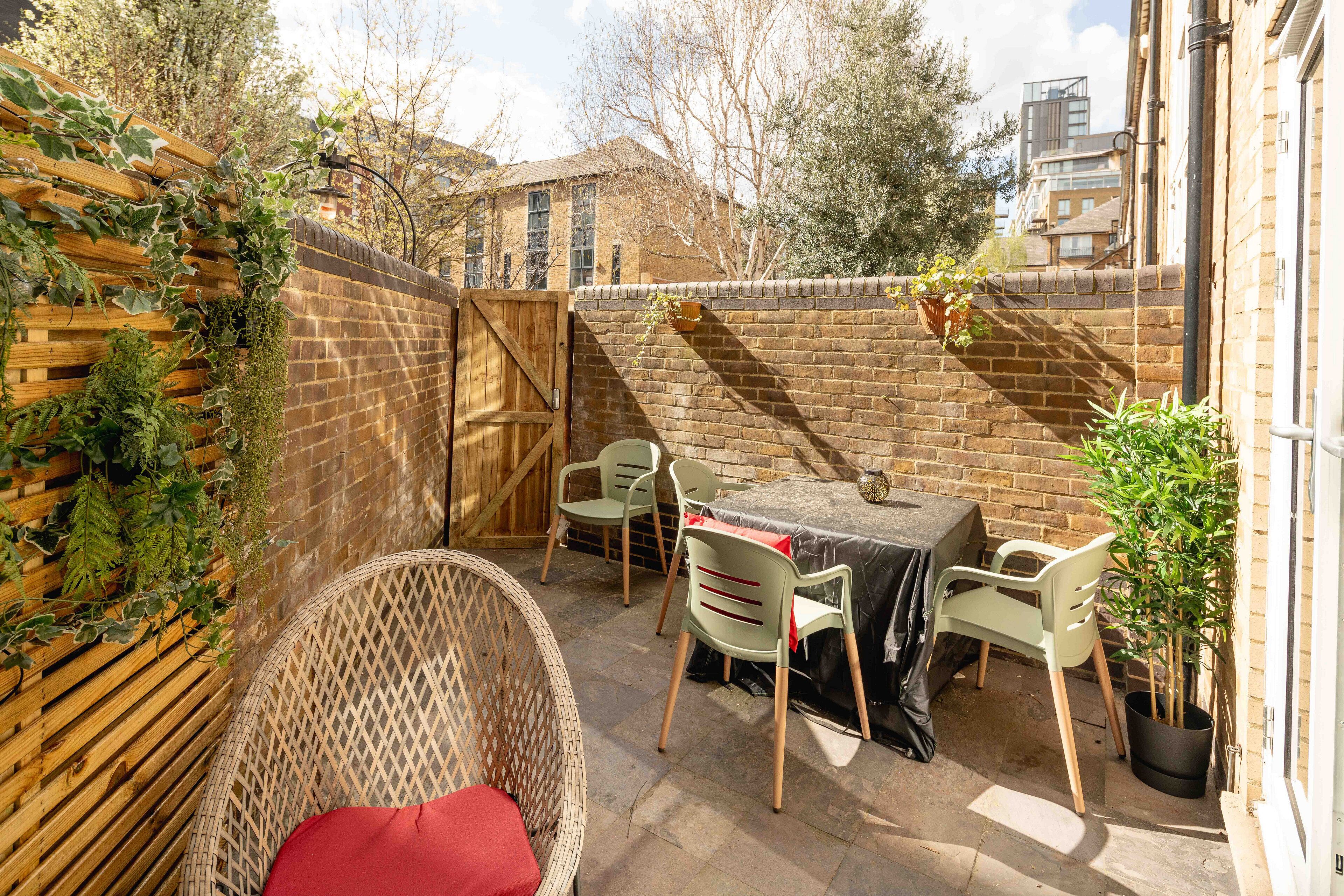 A patio area with a table, chairs, and potted plants.