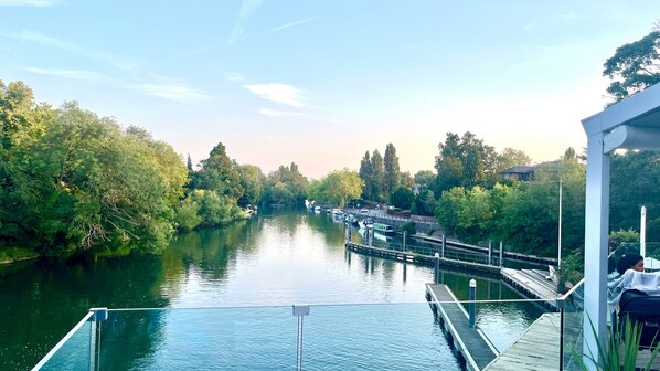 A riverside view with a wooden dock, boats, and lush greenery. - Modern 1 Bedroom Apt In Maidenhead Nr River Thames (Maidenhead)