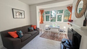Ein Wohnzimmer mit einer Couch, einem Esstisch und einem Fernseher.