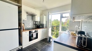 Eine moderne Küche mit weißen Schränken, einer schwarzen Küchenzeile, einem Einbauofen, einer Mikrowelle und einem Toaster.
