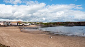 A beach with houses in the background, a clear sky, and people enjoying the water. - Historic 2Bd Maisonette In Coastal Eyemouth (Eyemouth)