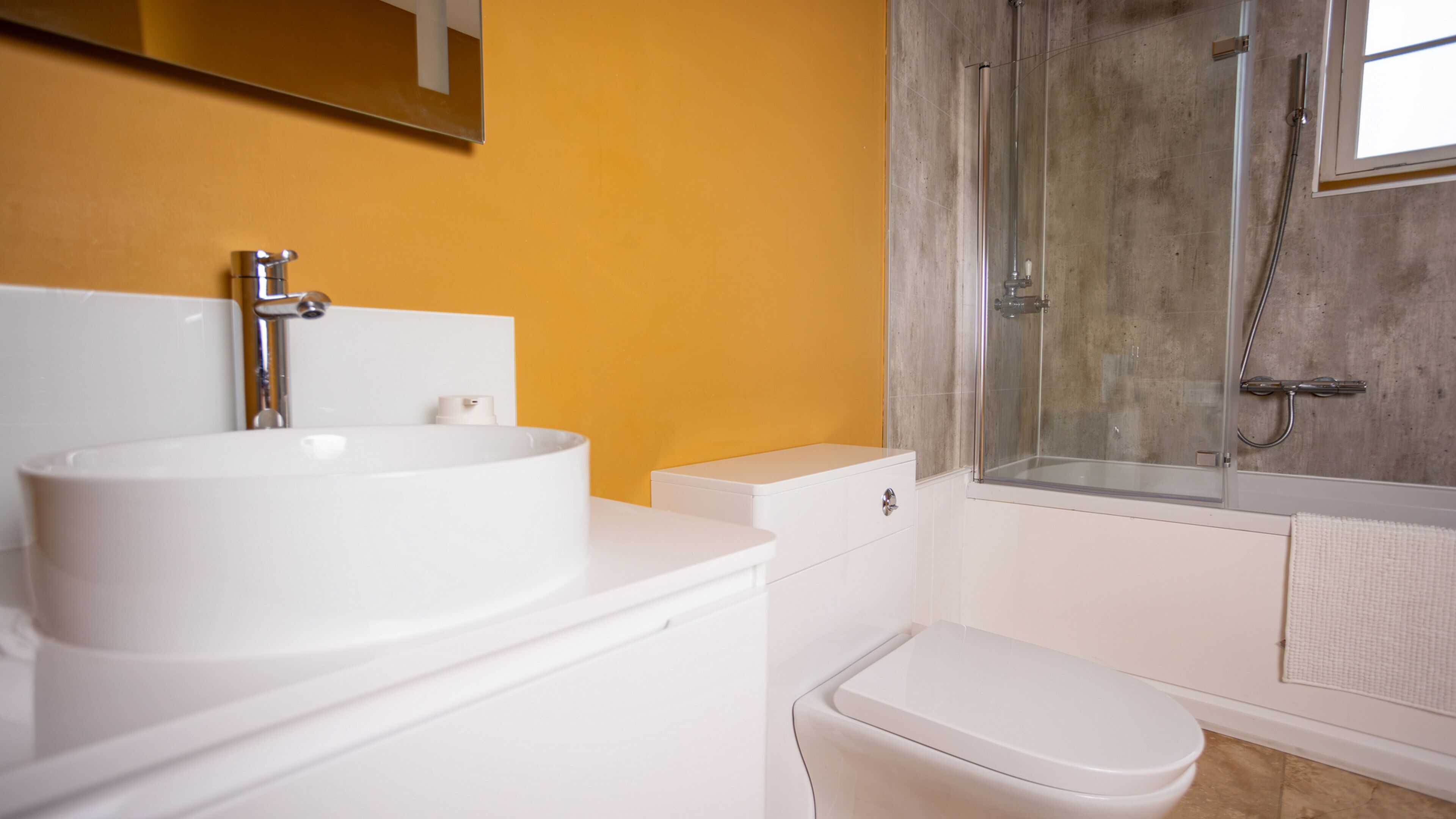 Een badkamer met een witte wastafel, toilet en douche.