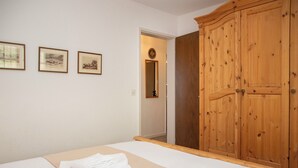 A bedroom with a bed, a wooden wardrobe, and three framed pictures on the wall. - La Siala Apt.51 by Interhome (Falera)
