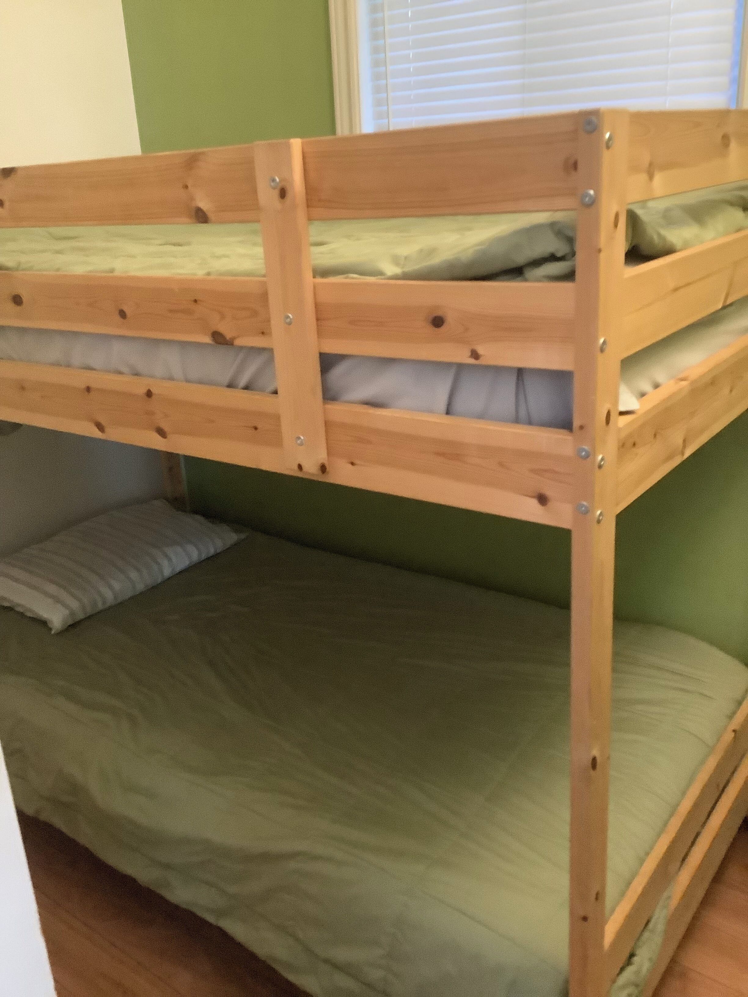 Een stapelbed met twee niveaus, elk voorzien van een matras en kussens.