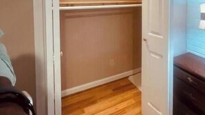 A small, open closet with wooden flooring and a white door. - Garden Annex (North Garden)
