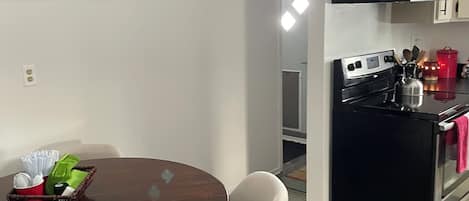Una cocina moderna con estufa, horno y armarios. Hay una mesa de comedor con sillas y una cesta de objetos encima.