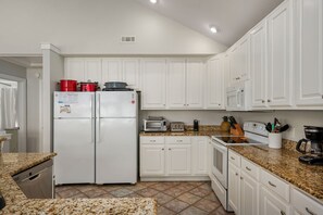 A kitchen with white cabinets, a double-door refrigerator, a microwave, a toaster, and a coffee maker. - Gone Coastal: Private Pool, Hot Tub, Ocean and Sunset Views! (Nags Head)