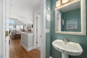 A room with a white ceiling fan, a clock, and a wall-mounted mirror with a decorative frame. - Gone Coastal: Private Pool, Hot Tub, Ocean and Sunset Views! (Nags Head)