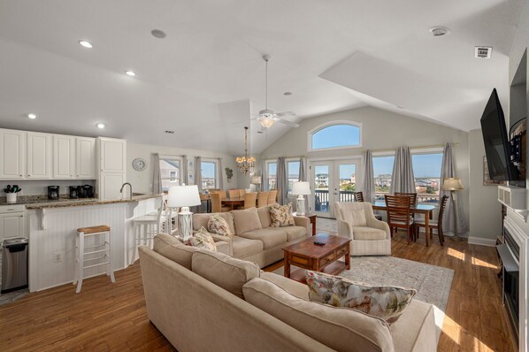 A spacious living area with a high ceiling, a dining area, and a kitchen. - Gone Coastal: Private Pool, Hot Tub, Ocean and Sunset Views! (Nags Head)