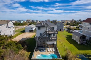 Un edificio residencial de varios pisos con terraza en la azotea, piscina y patio trasero cercado.