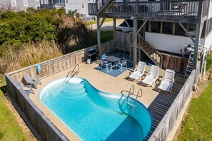 A swimming pool with a wooden deck, lounge chairs, and a covered patio area. - Gone Coastal: Private Pool, Hot Tub, Ocean and Sunset Views! (Nags Head)