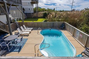 A backyard with a swimming pool, lounge chairs, and a wooden deck. - Gone Coastal: Private Pool, Hot Tub, Ocean and Sunset Views! (Nags Head)