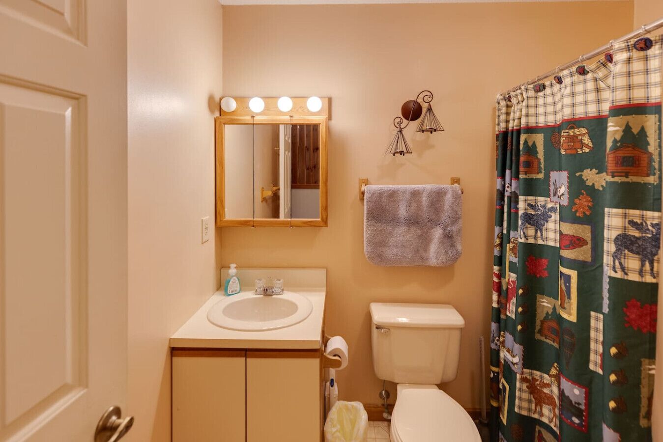 Un baño con lavamanos, espejo, inodoro y cortina de ducha con estampado escocés.