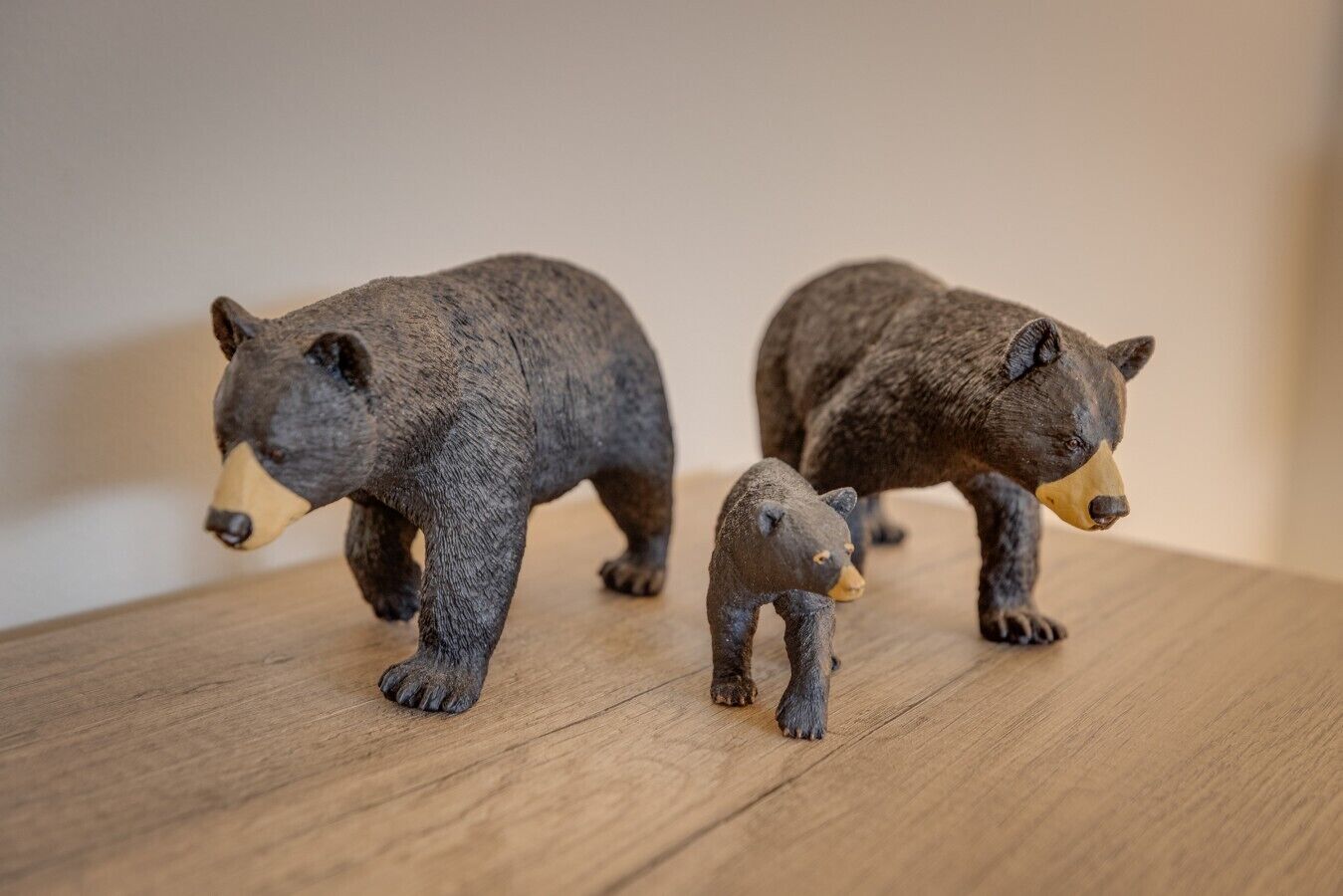 Trois statuettes d’ours sur une surface en bois.