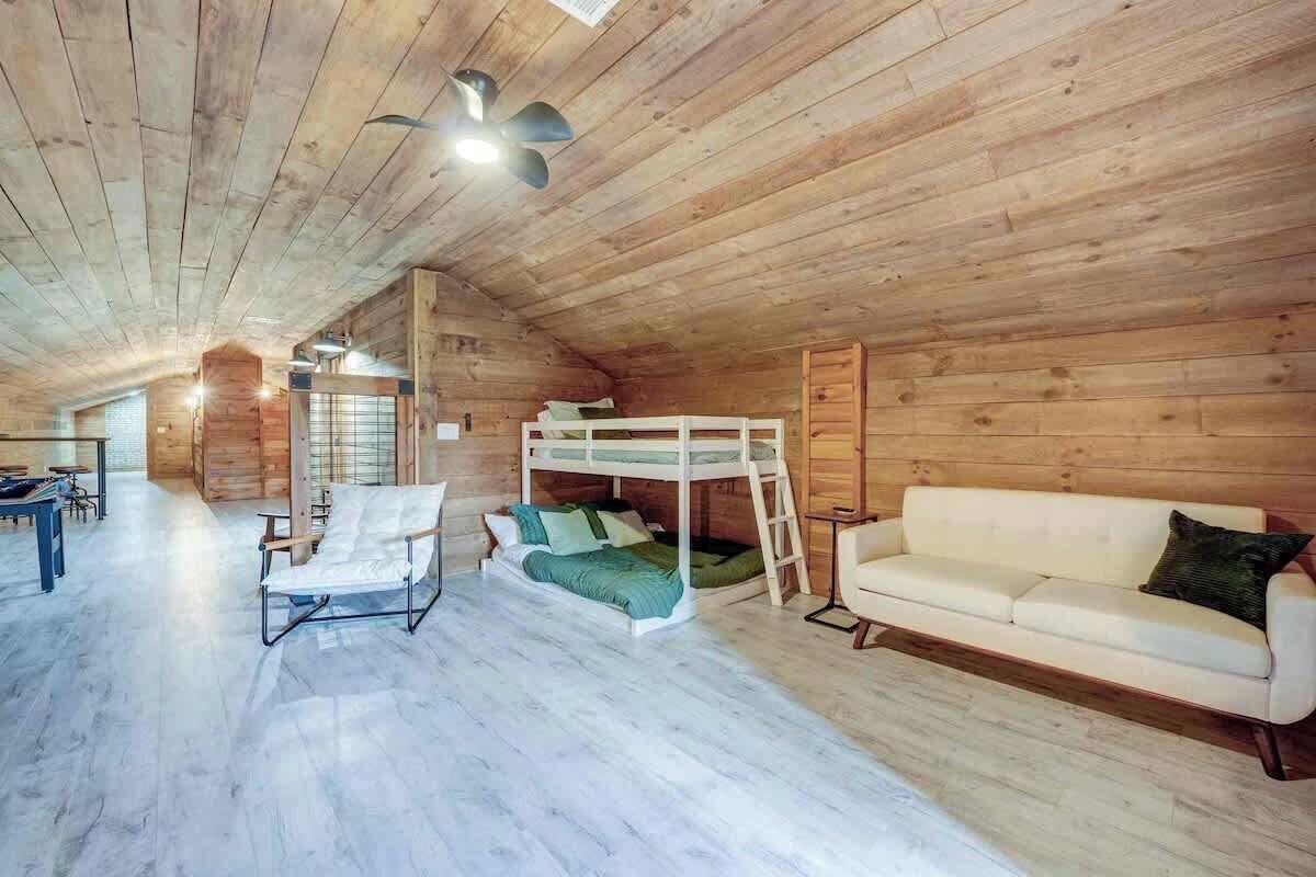 A wooden interior with a bunk bed, a sofa, and a chair.