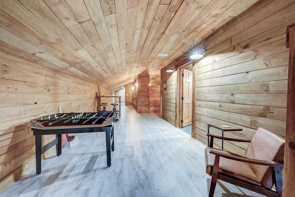 A wooden-floored corridor with a foosball table and a chair.