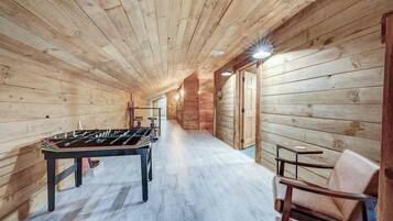 A wooden-floored corridor with a foosball table and a chair.