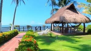 A beachside lounge with a thatched roof, a hammock, and a view of the ocean. - Tu casa de playa frente al mar en Tolú (Tolú)