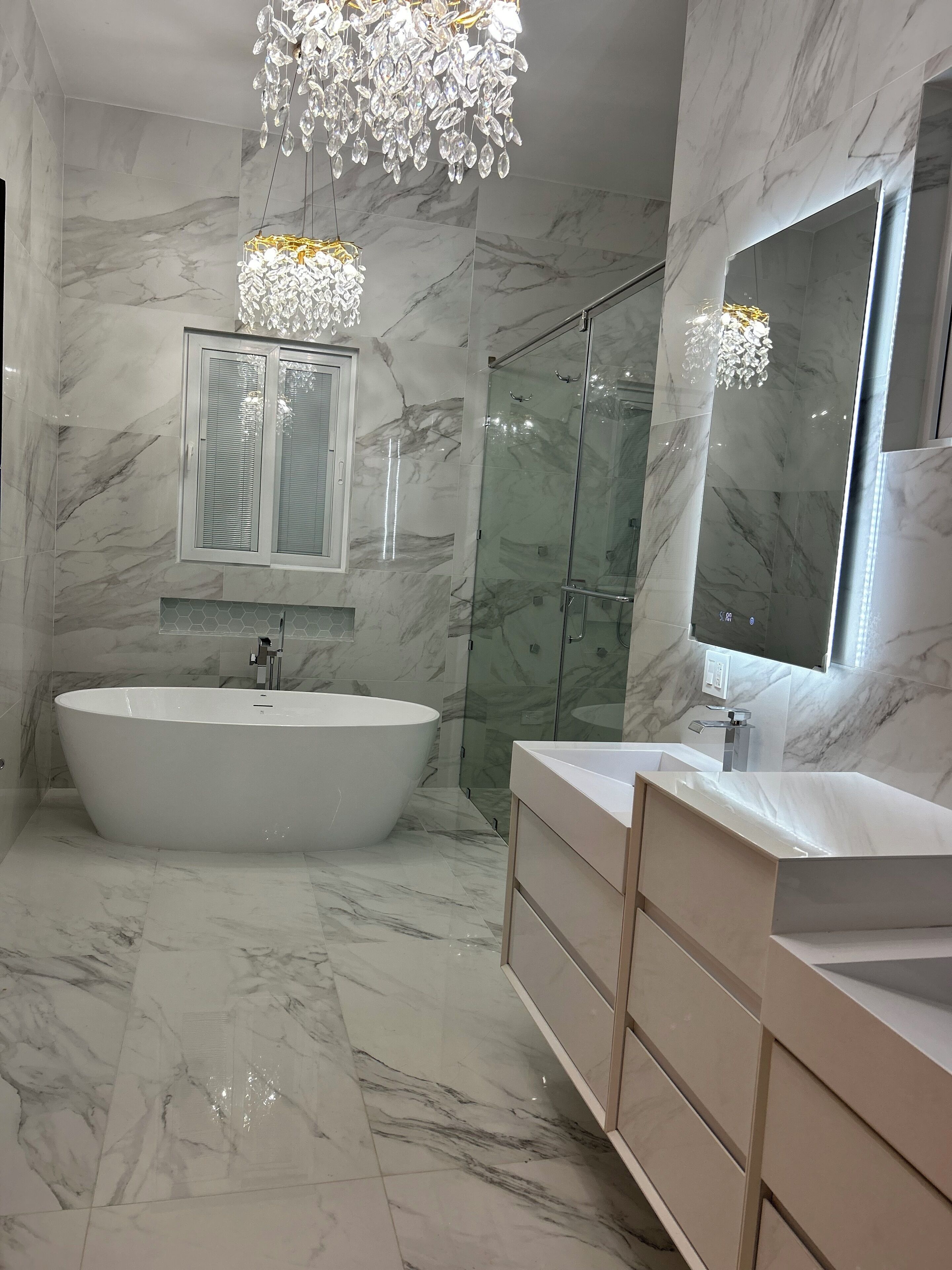 A modern bathroom with a freestanding bathtub, a glass-enclosed shower, and a vanity with a large mirror.