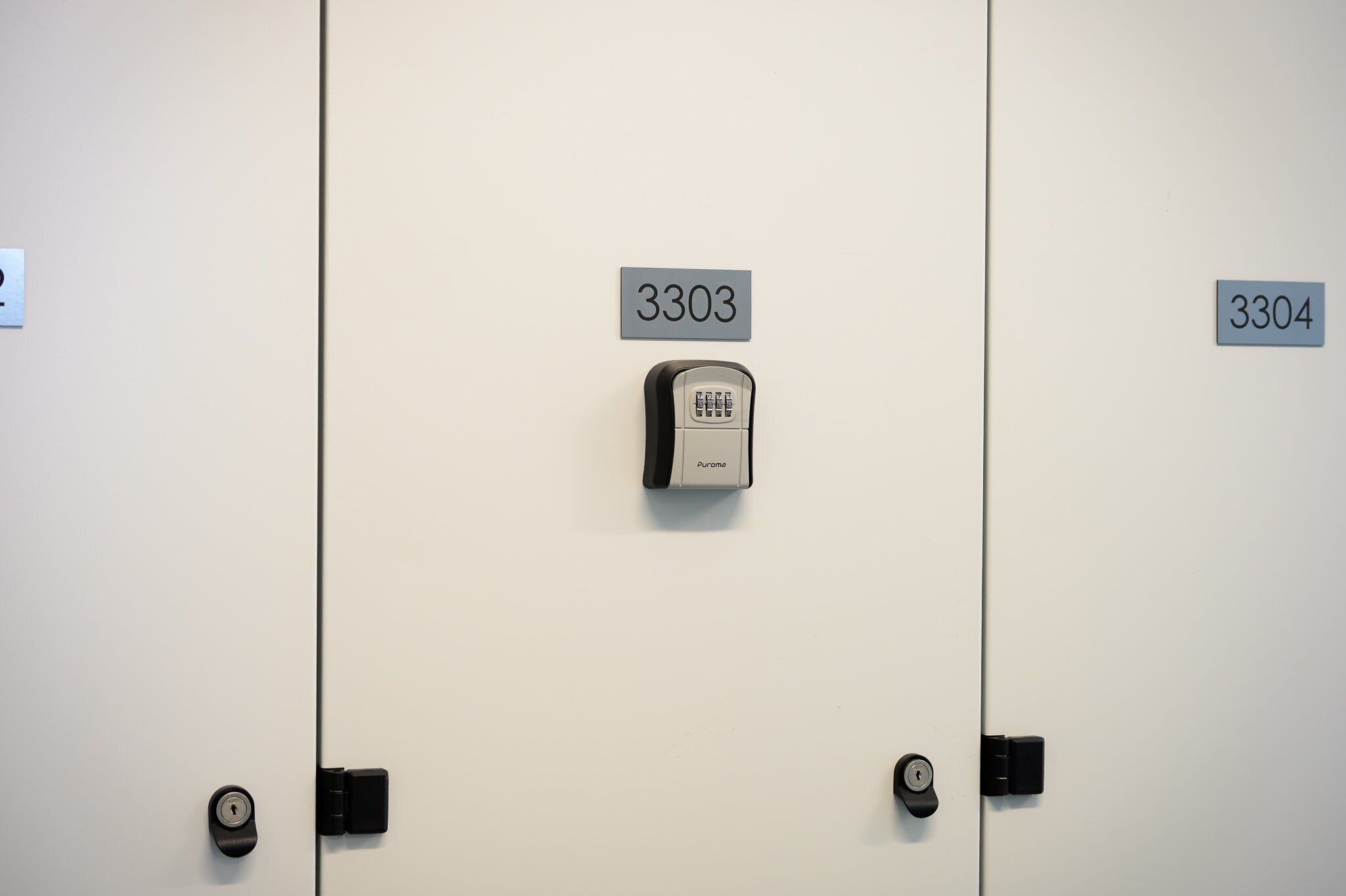 A row of hotel rooms with doors numbered 3303 and 3304, featuring a keypad lock and a standard key lock.