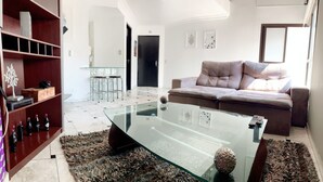 A modern living room with a glass coffee table, a sofa, and a bookshelf. - Entire Apartment - Duplex in Panamby (Vila Andrade São Paulo)