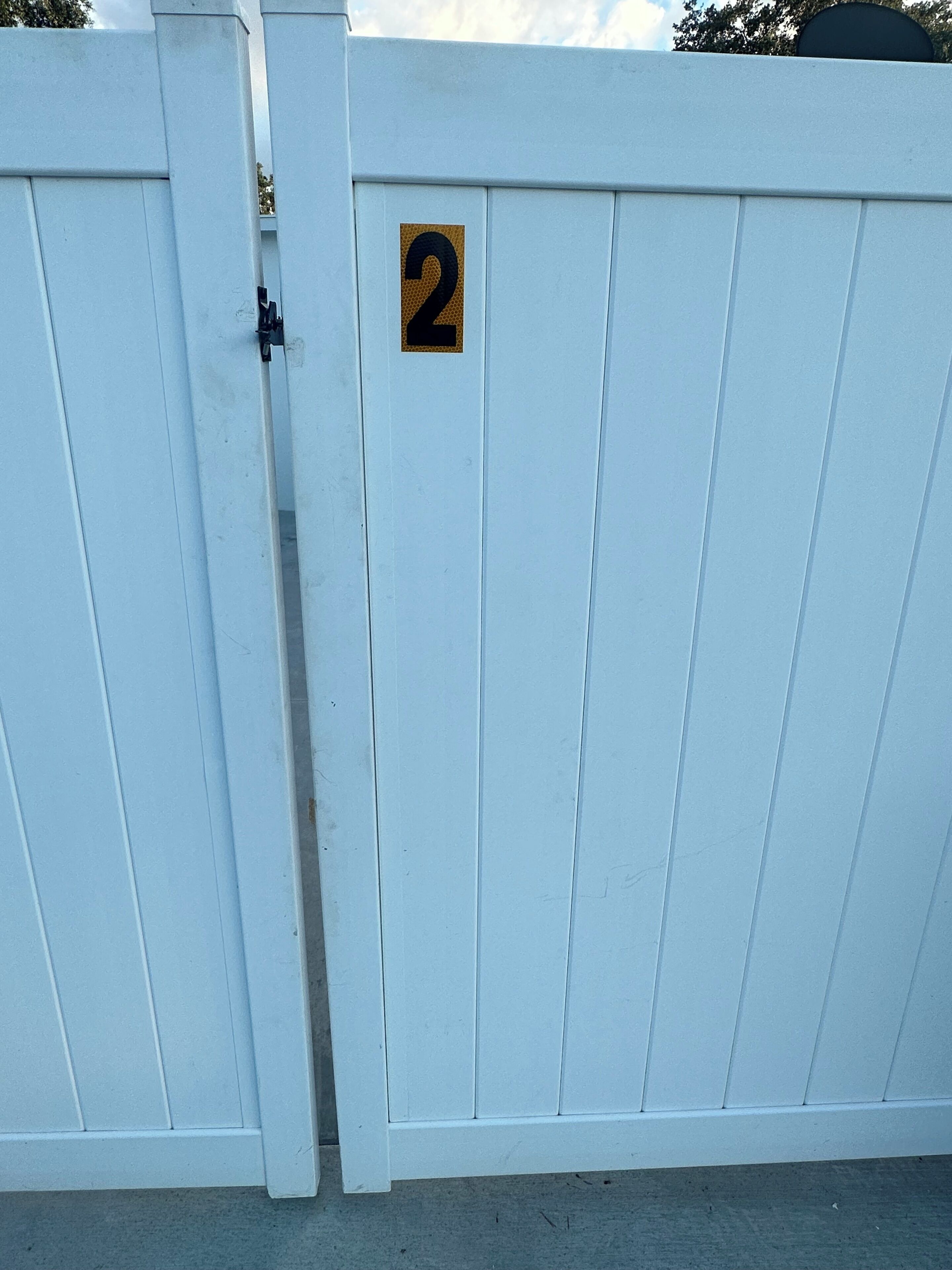 A white metal gate with a number '2' sign on it.