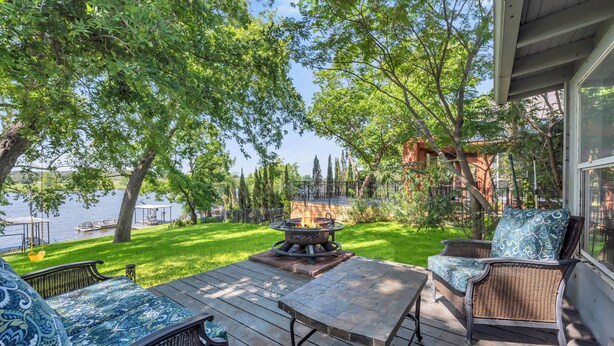 Una terraza con mobiliario exterior, una chimenea y vistas a un lago.