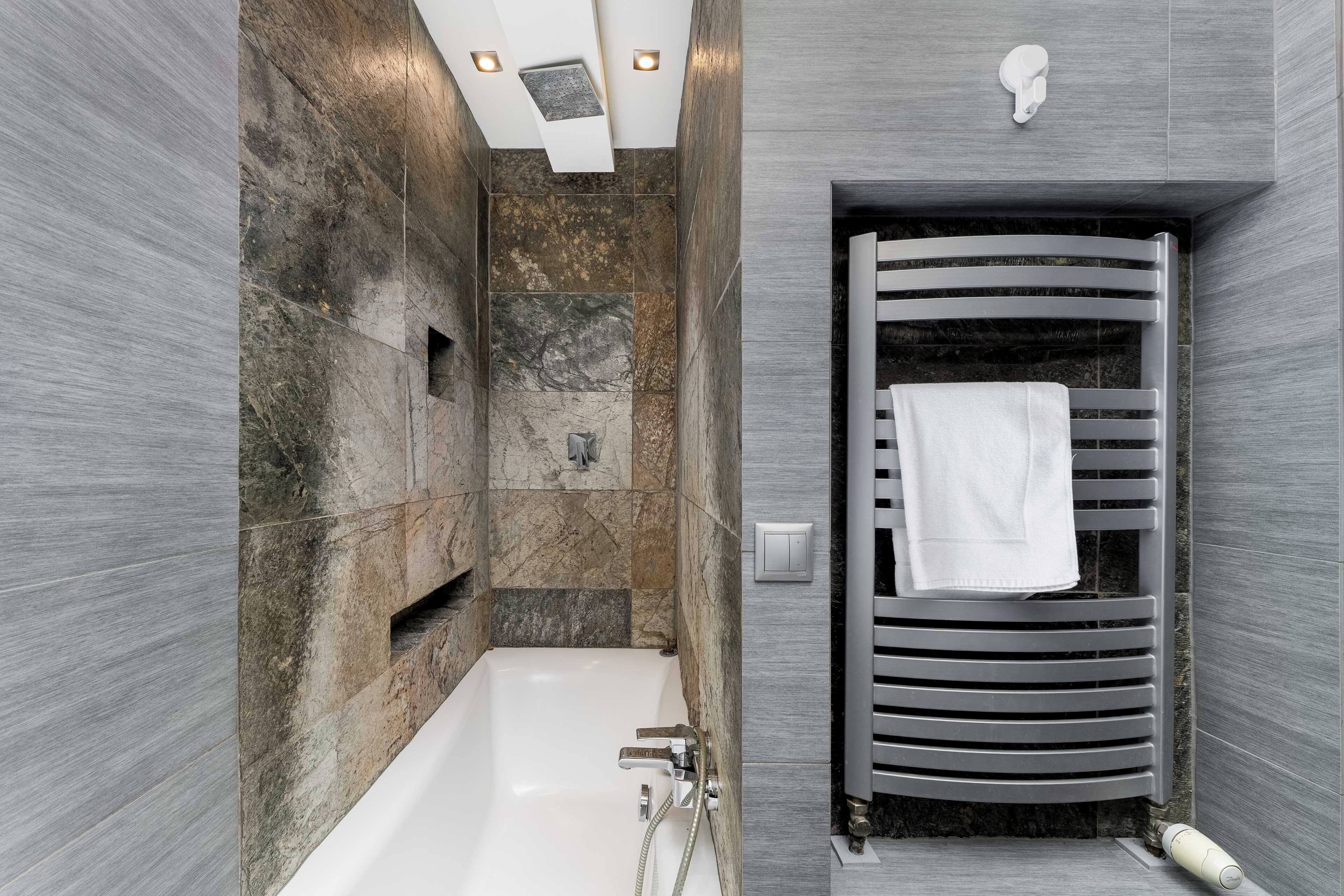 A modern bathroom with a bathtub, a towel rack, and a showerhead.