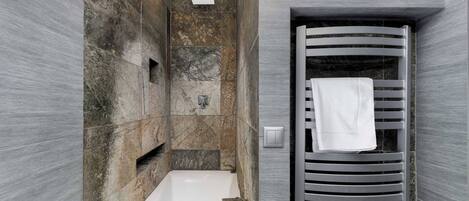 A modern bathroom with a bathtub, a towel rack, and a showerhead.