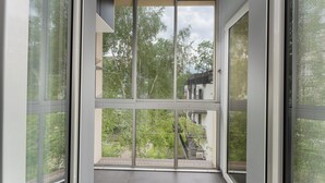 A modern interior with large floor-to-ceiling windows, a staircase, and a view of greenery outside. - Komorowskiego Riverside Apartment (Kraków)