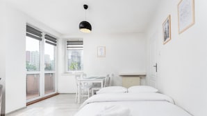 Ett minimalistiskt hotellrum med en stor säng, ett matbord och utsikt genom den skjutbara glasdörren.