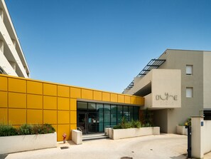 Een modern gebouw met een gele gevel, een glazen ingang en een bord waarop 'LA DUNE' staat.