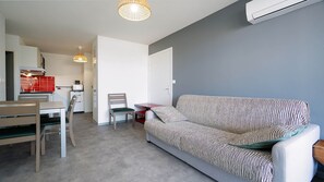 Un espacio habitable compacto con kitchenette, comedor y sofá con cojines a rayas.