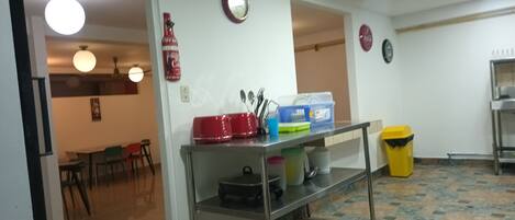 A kitchen area with a stainless steel counter, a red toaster, a blue container, and a yellow trash bin.
