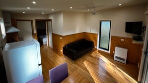 Un espacio habitable compacto con kitchenette, un sofá, un televisor y una ventana.