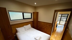 Un dormitorio con cama, armario de madera y ventana.