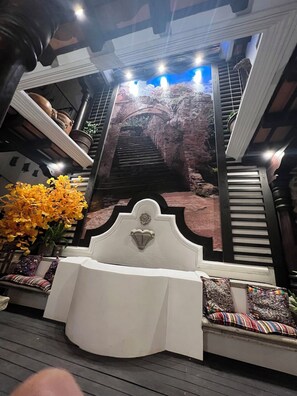 A room with a white sofa, a decorative wall with a staircase, and a potted plant with yellow flowers. - Stunning Casa Bella Vista Antigua downtown , 1 to 12 🙋AC, Wifi, lux rooftop Deck (Antigua Guatemala)