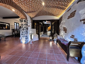 Un interior espacioso con techo alto, pilares de piedra y una combinación de decoración moderna y rústica.