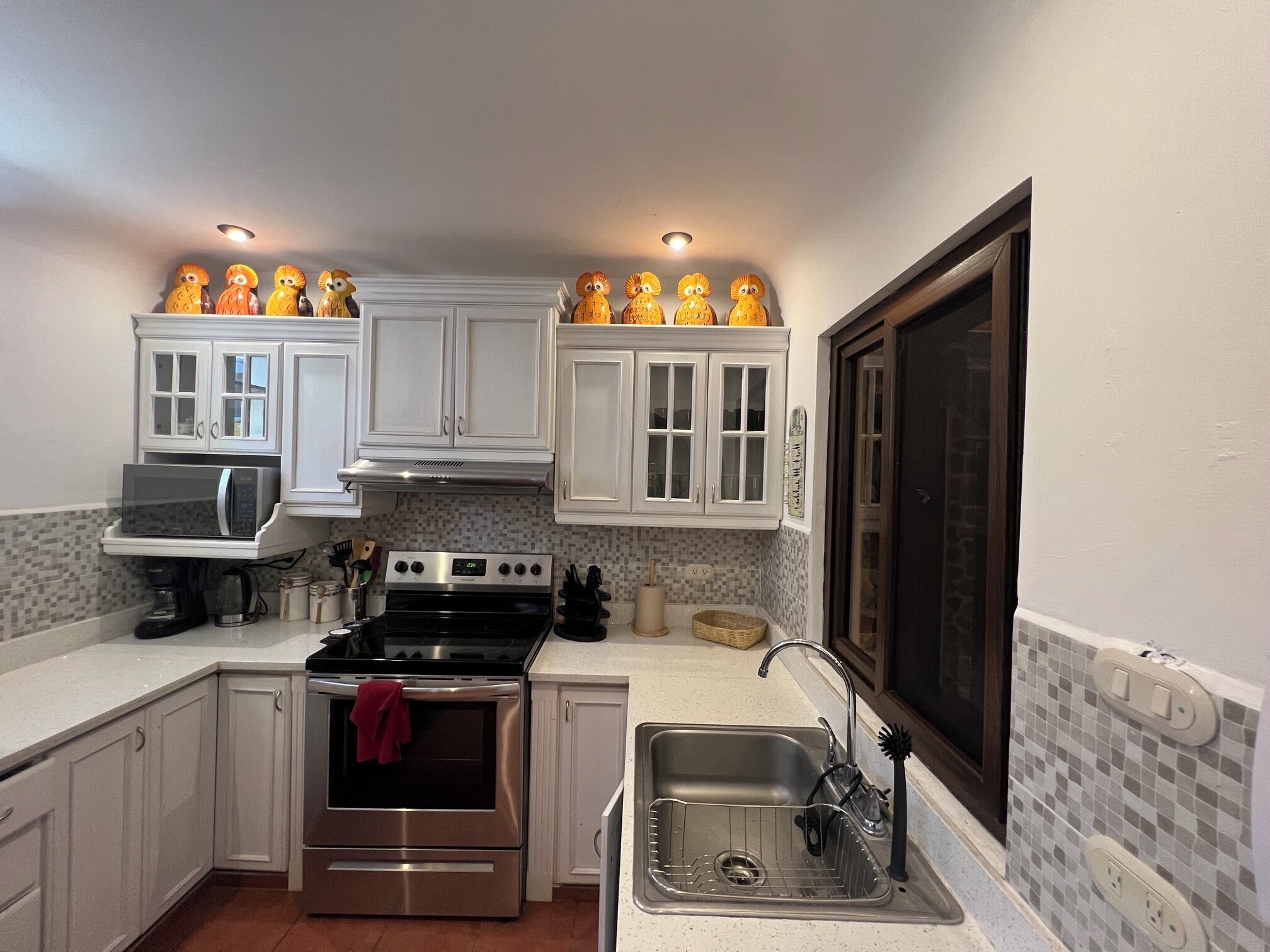 A kitchen with white cabinets, a stainless steel oven, a microwave, and a sink.