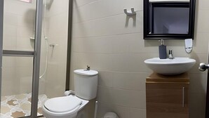 A bathroom with a toilet, sink, and shower area.