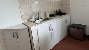 A kitchen with white cabinets, a sink, and a small refrigerator.
