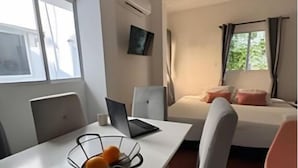 A compact hotel room with a bed, a desk with a laptop, and a chair.