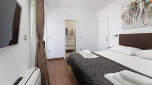 Et hotelværelse med seng, fjernsyn, badeværelse og et billede på væggen.
