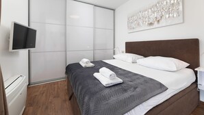 Ein modernes Hotelzimmer mit einem großen Bett, einem Flachbildfernseher und einem Schiebetürenschrank.