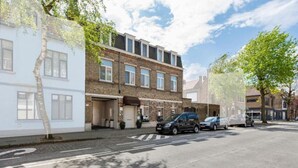 A street view with a row of two-story buildings, a parking area, and a pedestrian crossing. - Elegant room with private bathroom near city center (Brugge)