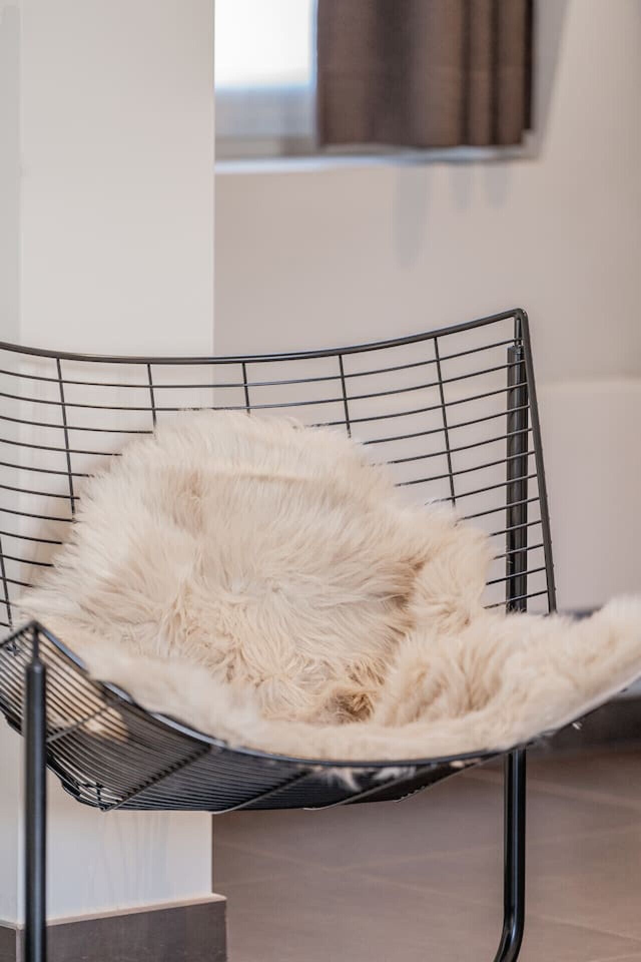 A modern chair with a metal frame and a fluffy white cushion.